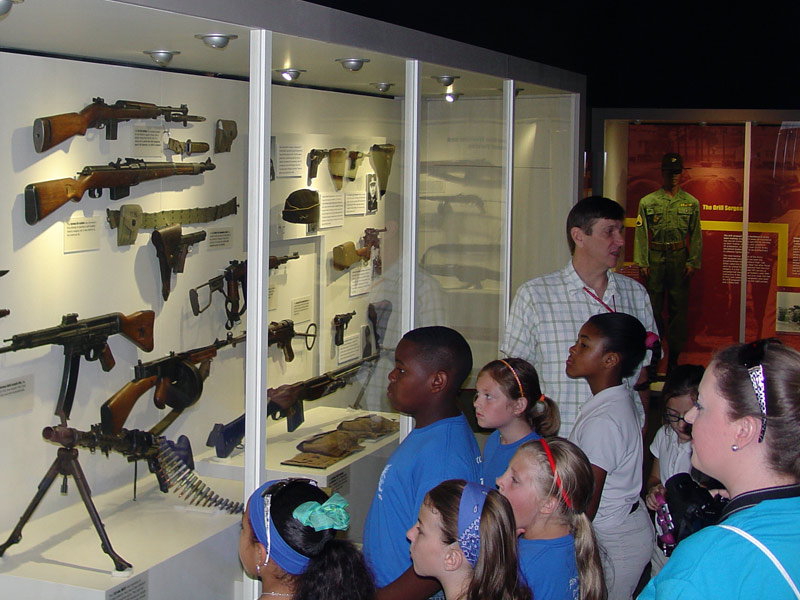 Children looking at museum artifacts inside a glass enclosure at the Fort Polk Museum.